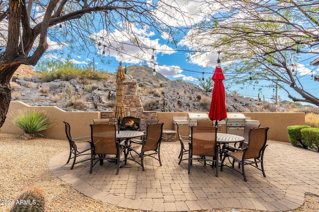 view of patio / terrace with a mountain view and an outdoor stone fireplace