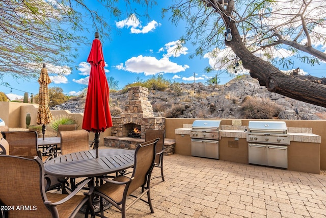 view of patio / terrace featuring an outdoor stone fireplace, an outdoor kitchen, and grilling area