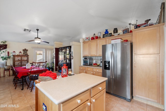 kitchen featuring light tile patterned floors, stainless steel refrigerator with ice dispenser, a kitchen island, decorative backsplash, and light brown cabinets