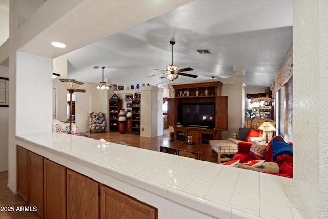 kitchen featuring lofted ceiling, tile countertops, and ceiling fan