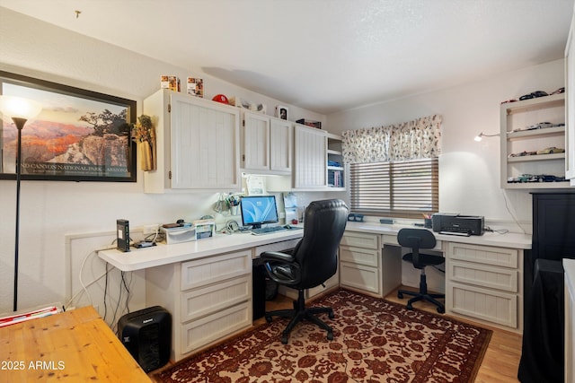 office with built in desk and light hardwood / wood-style floors