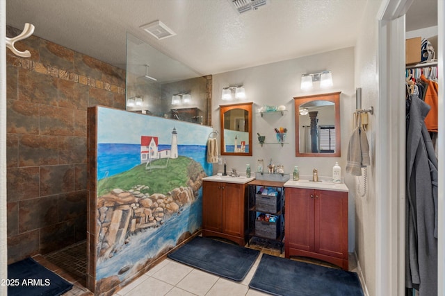 bathroom featuring tile patterned flooring, vanity, tiled shower, and a textured ceiling