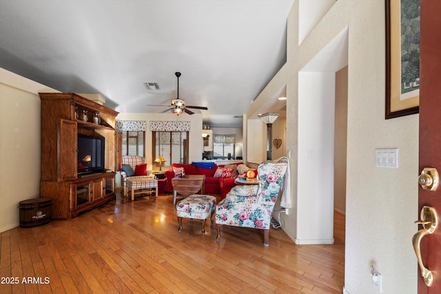 living room featuring vaulted ceiling, ceiling fan, and light hardwood / wood-style flooring