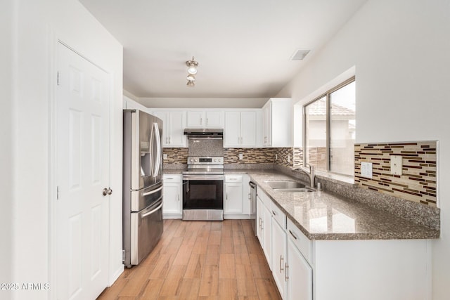 kitchen featuring under cabinet range hood, stainless steel appliances, a sink, white cabinets, and light wood finished floors