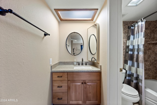 full bathroom featuring a skylight, shower / bath combination with curtain, vanity, and toilet