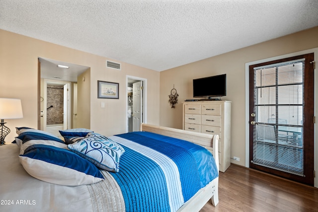 bedroom featuring ensuite bath, a textured ceiling, and dark hardwood / wood-style floors