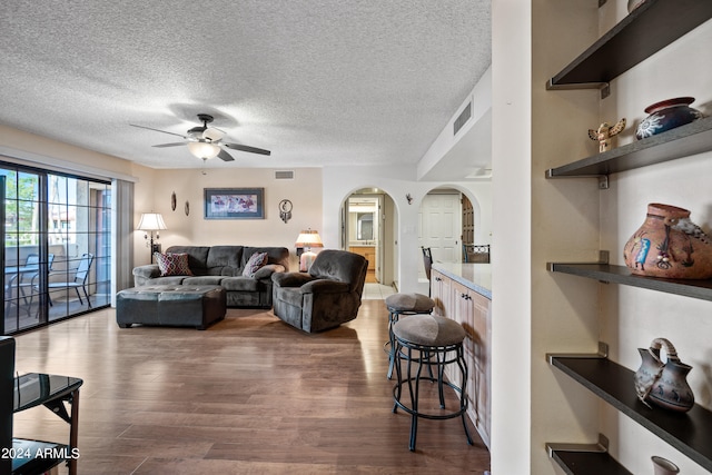 living room featuring a textured ceiling, ceiling fan, and dark hardwood / wood-style flooring