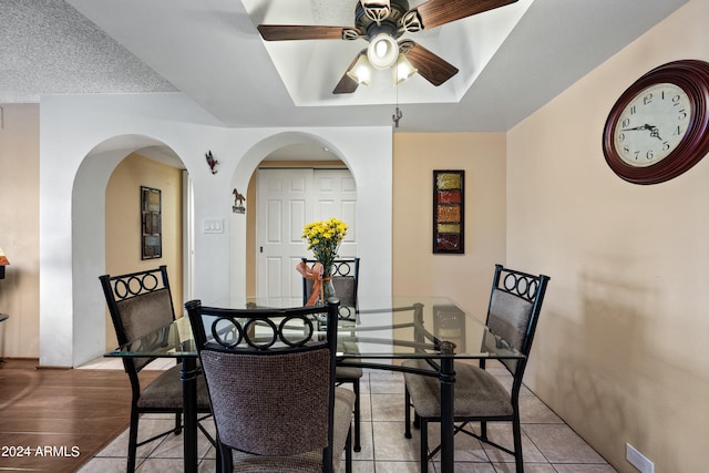 dining space featuring light wood-type flooring, ceiling fan, a raised ceiling, and a textured ceiling