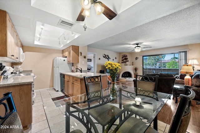 tiled dining space with a textured ceiling, sink, track lighting, and ceiling fan