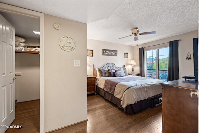 bedroom with a textured ceiling, dark hardwood / wood-style flooring, ceiling fan, and access to exterior