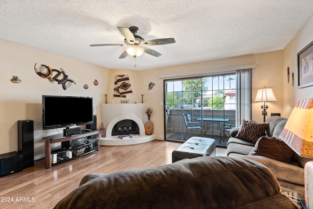 living room with a textured ceiling, light hardwood / wood-style floors, and ceiling fan