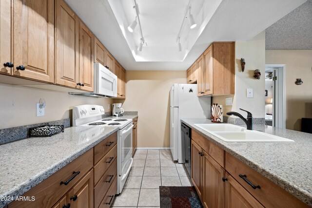 kitchen with light tile patterned flooring, sink, rail lighting, white appliances, and light stone countertops