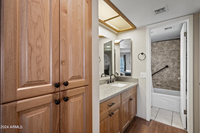 bathroom featuring wood-type flooring, tiled shower / bath, and vanity