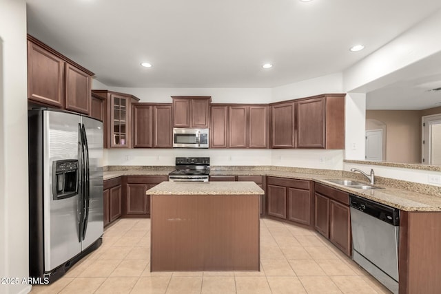 kitchen featuring light tile patterned floors, kitchen peninsula, stainless steel appliances, a kitchen island, and sink