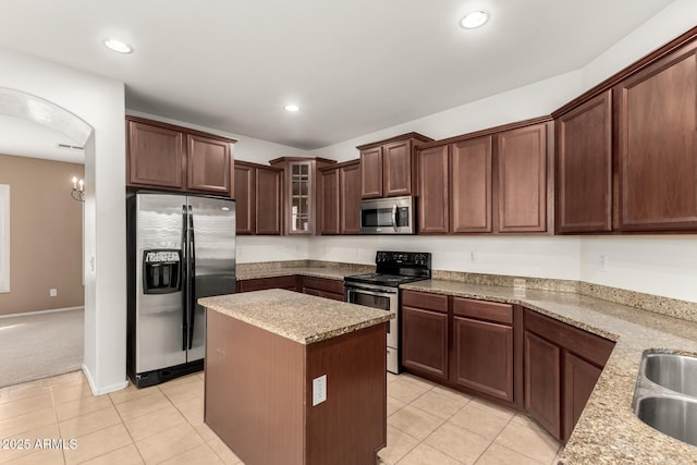 kitchen featuring light stone counters, light tile patterned floors, appliances with stainless steel finishes, and a kitchen island