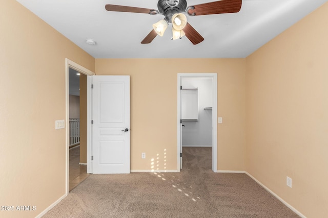 unfurnished bedroom with ceiling fan, light carpet, a closet, and a walk in closet