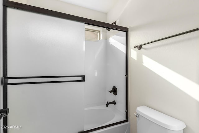 bathroom featuring toilet and bath / shower combo with glass door