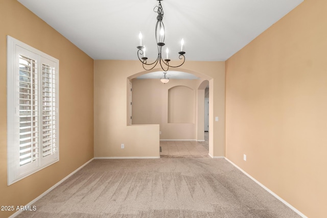 carpeted spare room featuring a chandelier