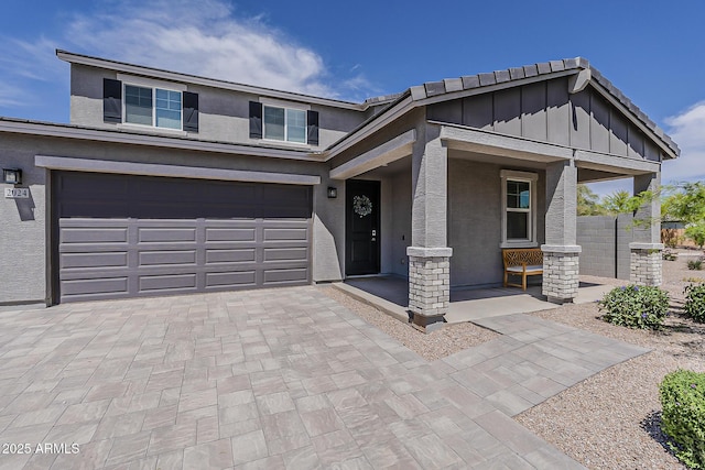 view of front of property with covered porch, a garage, board and batten siding, stucco siding, and decorative driveway