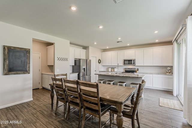 dining space with recessed lighting, wood finished floors, visible vents, and baseboards