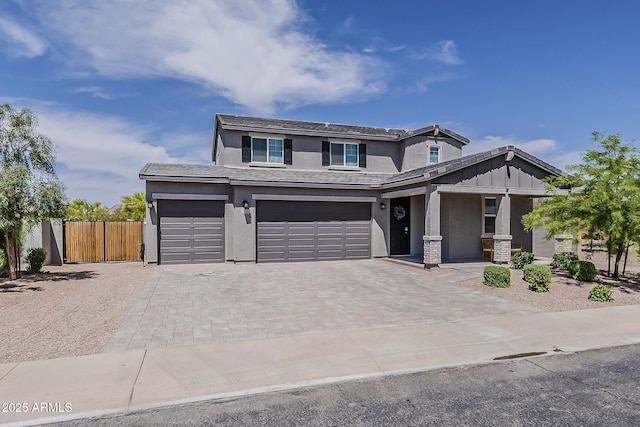view of front of house with covered porch, fence, an attached garage, stucco siding, and decorative driveway