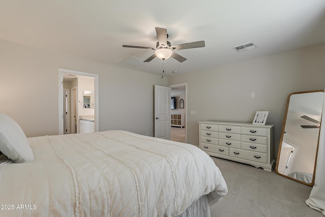 carpeted bedroom featuring ensuite bath, visible vents, and ceiling fan