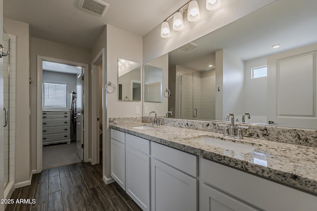 bathroom featuring wood finished floors, visible vents, a sink, and a stall shower