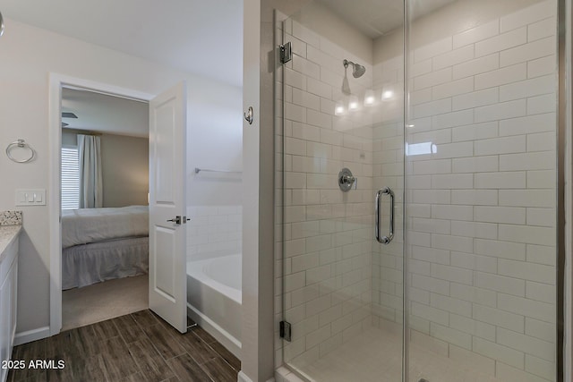 ensuite bathroom featuring a shower stall, wood finished floors, a garden tub, and connected bathroom