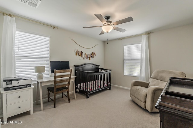bedroom featuring baseboards, visible vents, light colored carpet, a ceiling fan, and a nursery area