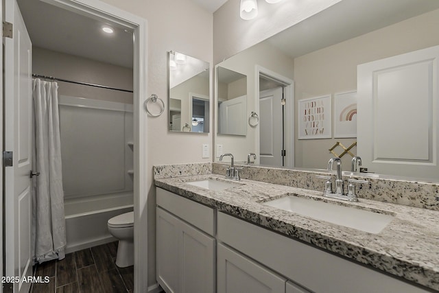 full bath featuring toilet, wood finished floors, a sink, and double vanity