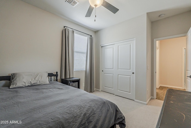 bedroom featuring a closet, ceiling fan, light carpet, baseboards, and visible vents