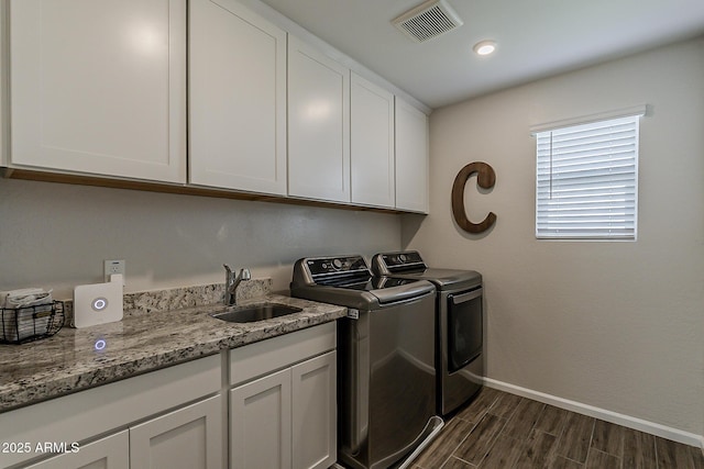 washroom featuring a sink, washing machine and dryer, baseboards, dark wood-type flooring, and visible vents