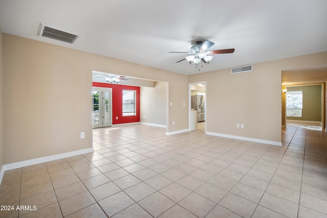 empty room with ceiling fan, a healthy amount of sunlight, and light tile patterned floors