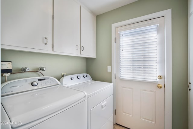 laundry area with independent washer and dryer and cabinets