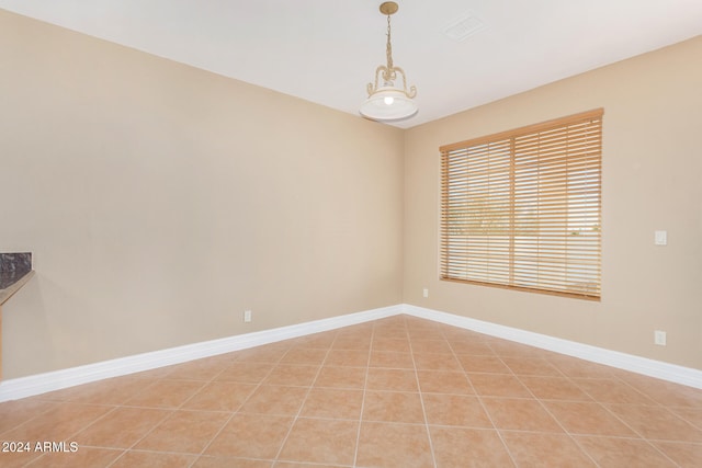 spare room featuring a notable chandelier and light tile patterned flooring