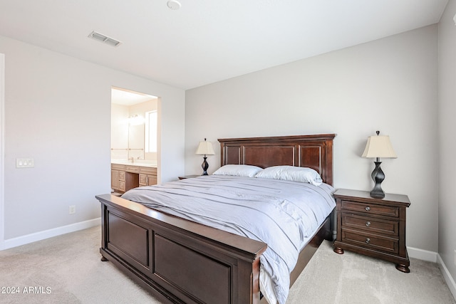 bedroom featuring light colored carpet and ensuite bath