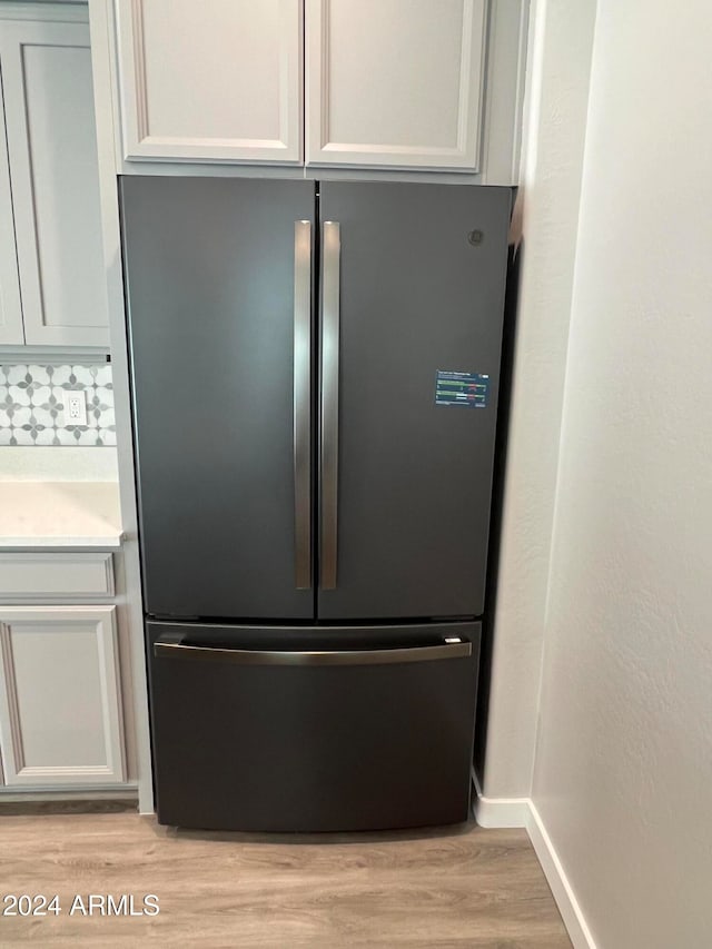 interior details featuring white cabinetry, stainless steel refrigerator, and light wood-type flooring