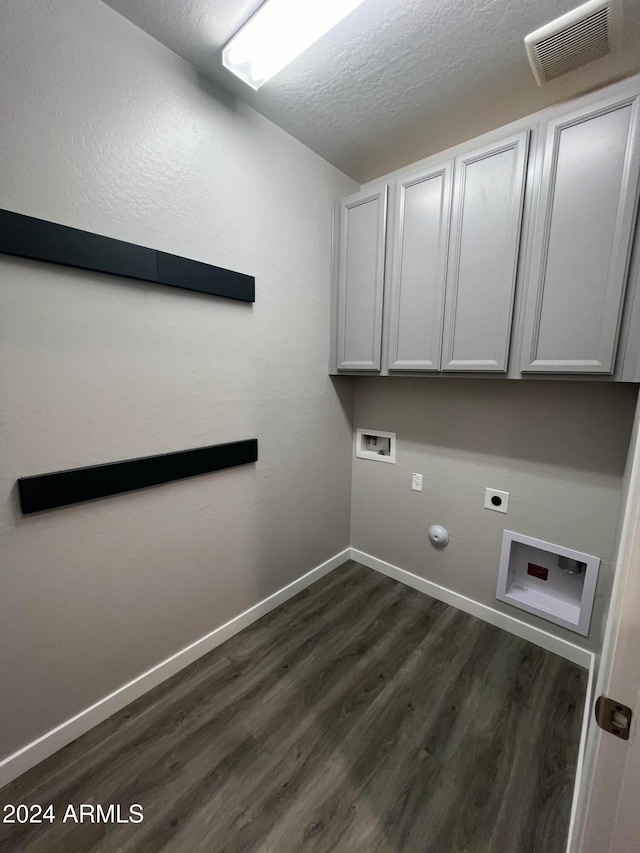 clothes washing area with hookup for a gas dryer, electric dryer hookup, washer hookup, dark wood-type flooring, and cabinets