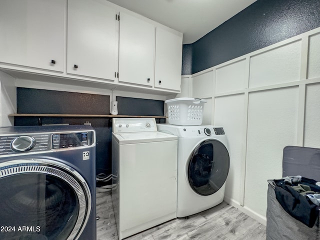 washroom featuring cabinets, separate washer and dryer, and light hardwood / wood-style flooring