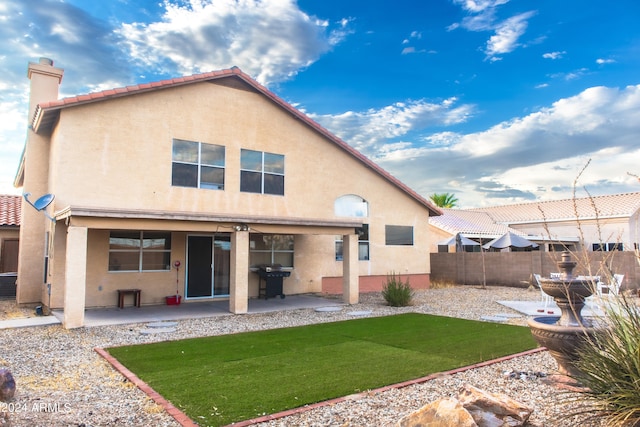 rear view of house featuring a lawn and a patio area