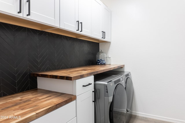 laundry area featuring hardwood / wood-style flooring, cabinets, and washing machine and clothes dryer