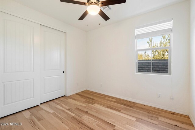 unfurnished bedroom with ceiling fan, light hardwood / wood-style floors, and a closet