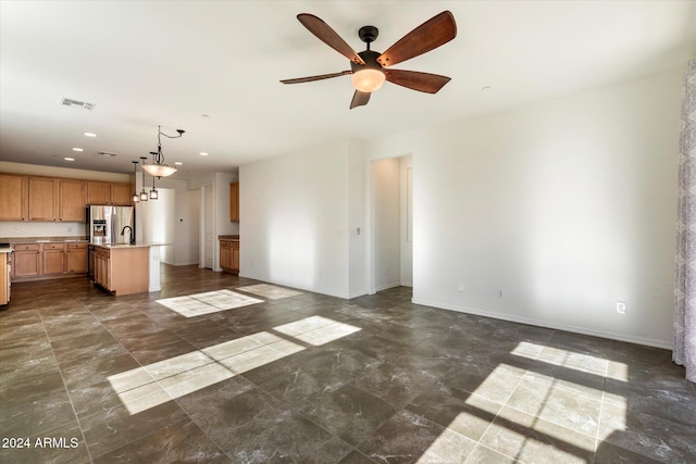 unfurnished living room featuring ceiling fan and sink