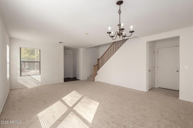 carpeted spare room with visible vents, stairway, and a chandelier