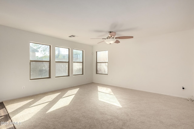 unfurnished room featuring ceiling fan, visible vents, baseboards, and light colored carpet