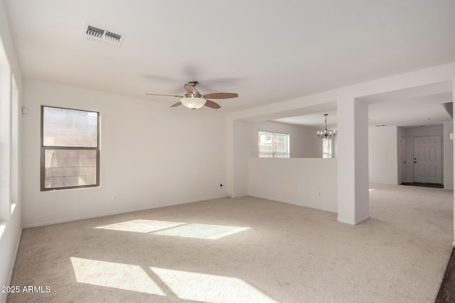 carpeted empty room with baseboards, visible vents, and ceiling fan with notable chandelier