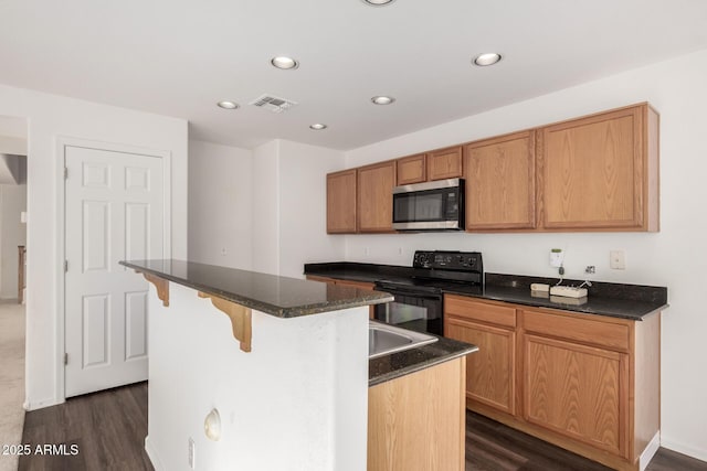 kitchen featuring visible vents, stainless steel microwave, dark wood-style flooring, black range with electric cooktop, and a kitchen bar