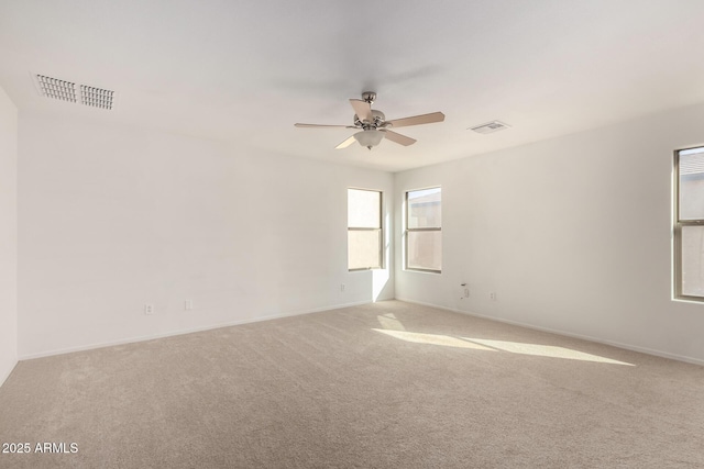carpeted empty room with ceiling fan, visible vents, and baseboards