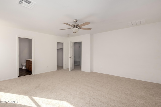 unfurnished bedroom featuring light carpet, ensuite bath, and visible vents