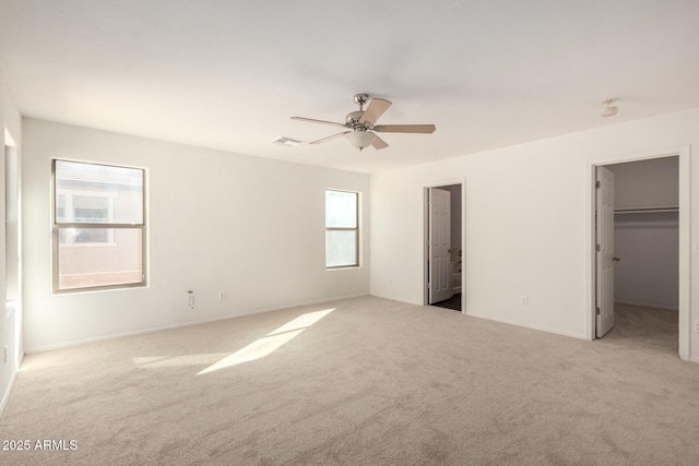unfurnished bedroom featuring carpet floors, a walk in closet, visible vents, and ceiling fan
